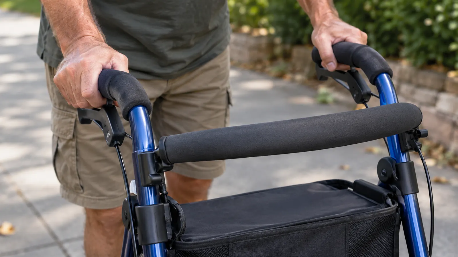 Hands gripping the rollator's foam handles on a paved sidewalk