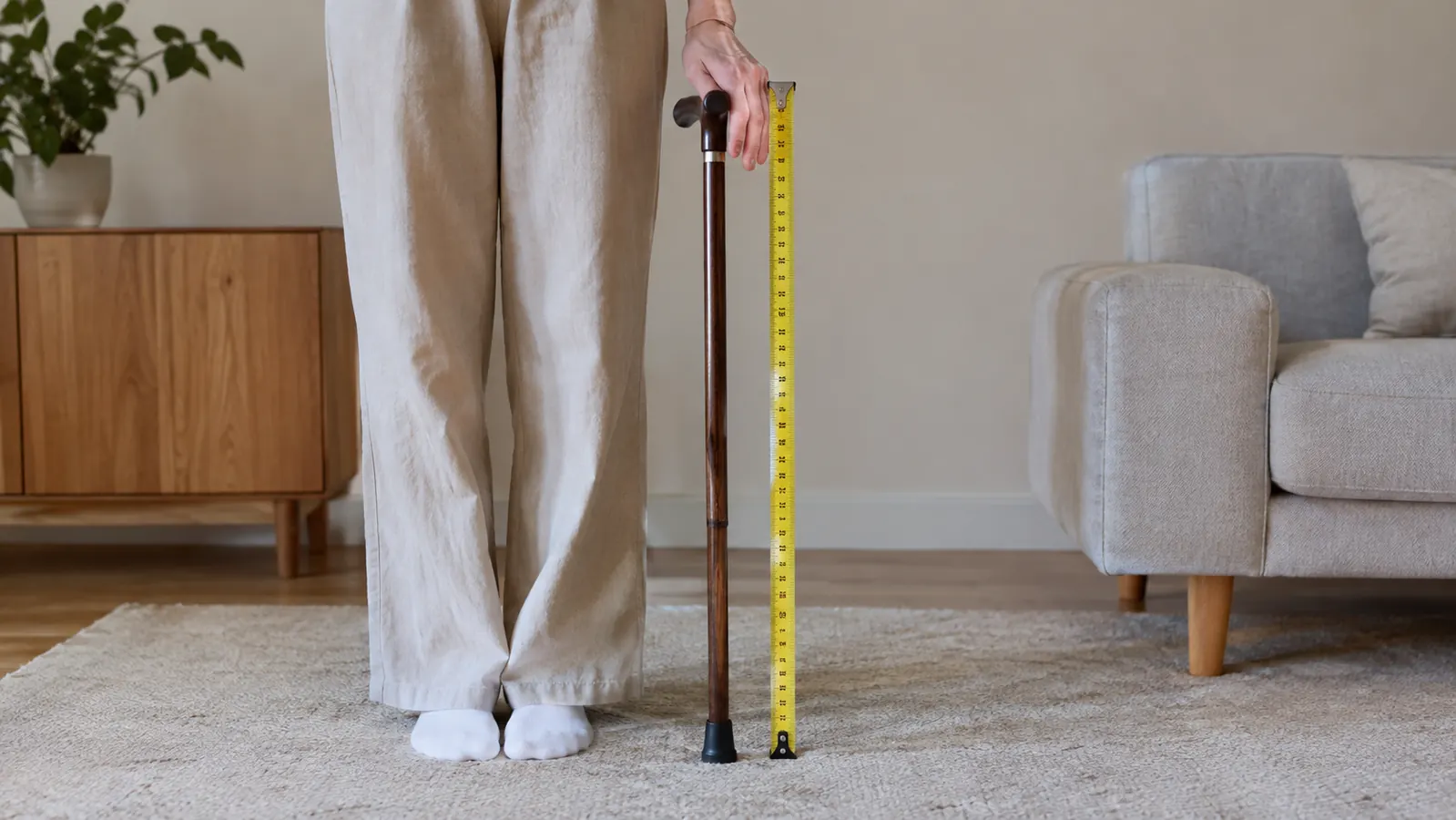 A measuring tape lying beside a cane on a rug, showing how to measure from the floor to the wrist crease