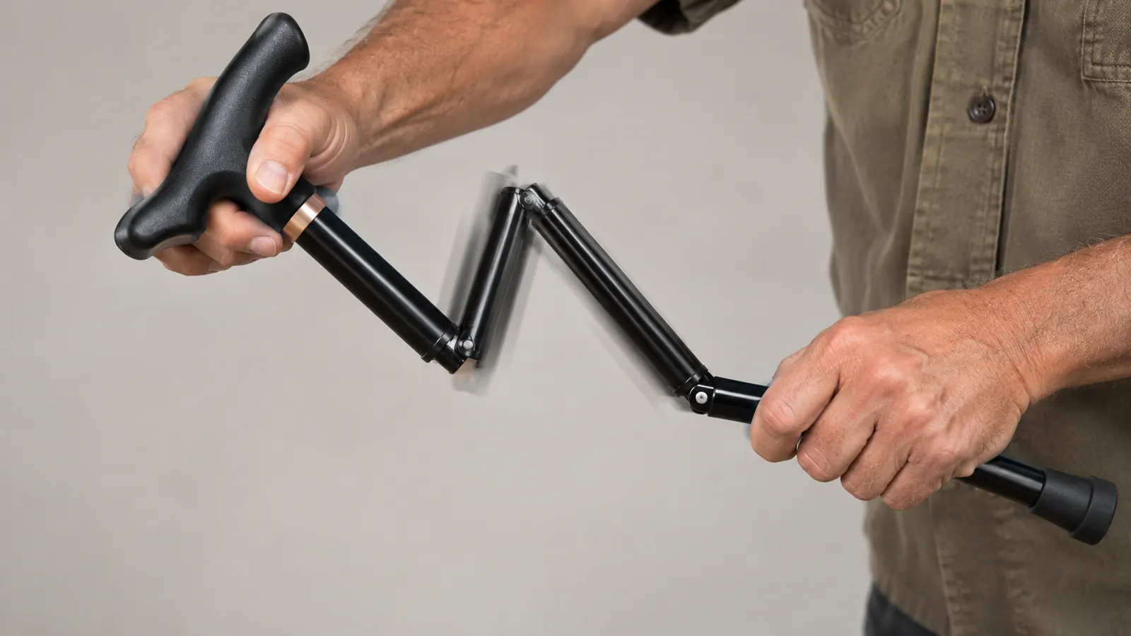 Close view of hands opening the folding sections of a cane with a T handle, one hand on the shaft and one on the handle