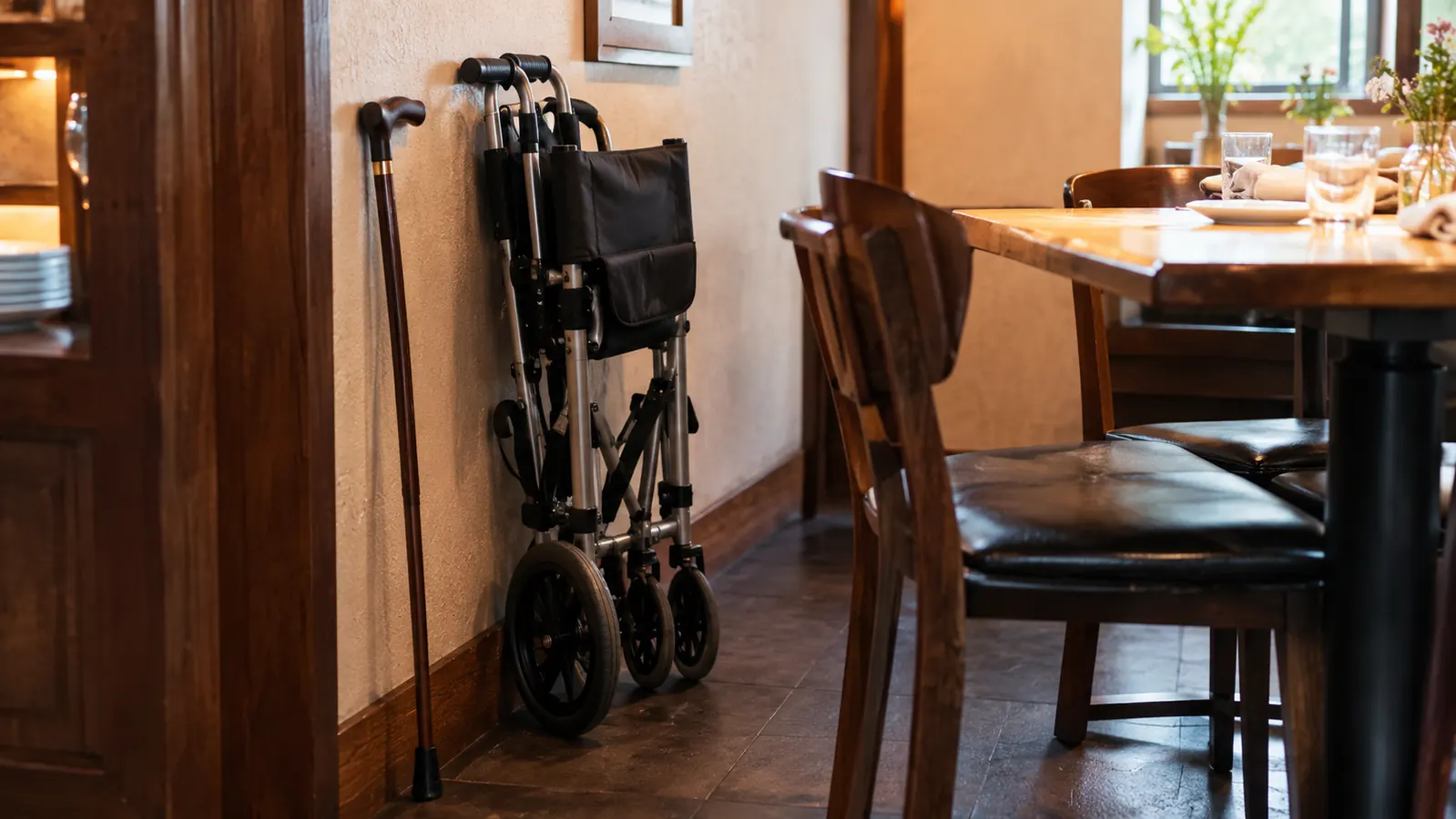 A transport chair parked beside a restaurant table in a narrow dining room
